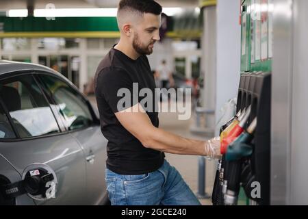 Man bereitet sich auf das Betanken an der Tankstelle vor. Männliche Hand Füllen Benzin Benzin Kraftstoff im Auto. Konzept der Benzinpreise Stockfoto