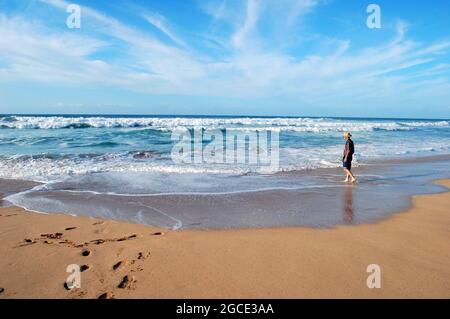 Männlicher Tourist, mit aufgerollten Jeans, genießt die Einsamkeit des Polihale State Park auf der Insel Hawaii. Er trägt einen Strohhut. Stockfoto