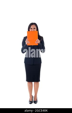 Lächelnde asiatische moderne Geschäftsfrau hält Buch und versteckt hinter dem Buch, Blick auf die Kamera, Ganzkörperportrait isoliert auf weißem Hintergrund Stockfoto