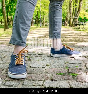 Junge Person in Turnschuhen, die auf der gepflasterten Straße läuft. Tourismuszeit Stockfoto