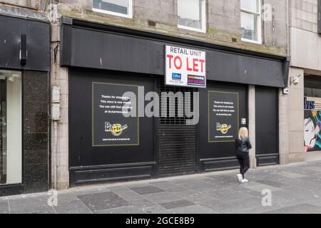 Frau (Bewegung verschwommen), die an dem geschlossenen Geschäft von Dr. Marten in der Union Street, Aberdeen, vorbeigeht. Stockfoto