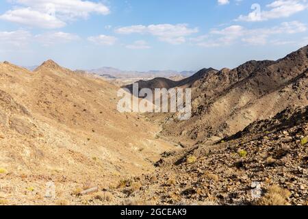 Al Hajar Mountains Landschaft vom Copper Hike Summit aus gesehen, mit felsigem, trockenem Flussbett (wadi) und kargen Bergrücken, Hatta, Vereinigte Arabische Emirate. Stockfoto