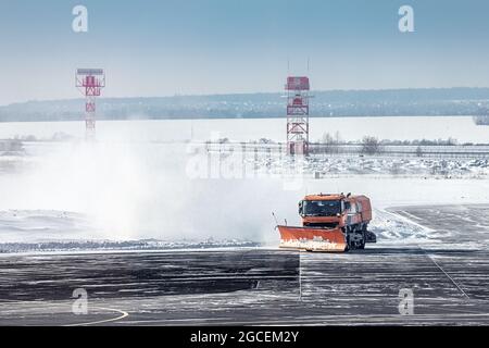 Schneepflug-Lastwagen räumen Schneeverwehungen nach einem schweren Sturm Schneesturm am Winterflughafen. Das Konzept der sich ändernden Wetterbedingungen und Flugverspätungen Stockfoto