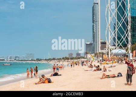 22. Februar 2021, Dubai, VAE: Menschenmassen spazieren am Sandstrand von JBR oder Jumeirah Beach Residence entlang. Urlauber schwimmen und sonnen sich Stockfoto