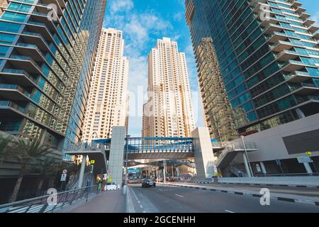 21. Februar 2021, Dubai, VAE: Jumeirah Beach Residence Block und eine Straße mit Autos zwischen Hochhäusern und Wolkenkratzern Stockfoto