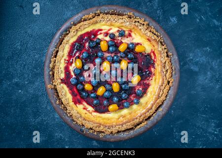 Blaubeere und Sanddorn-Käsekuchen auf dunklem Hintergrund, Draufsicht, Nahaufnahme Stockfoto