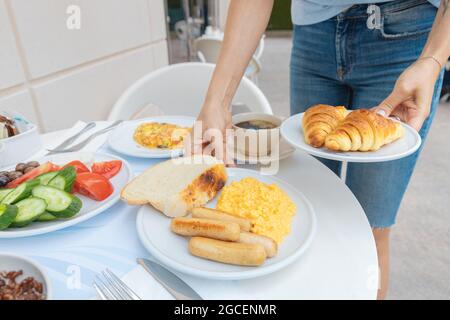 Während des Frühstücks im Hotel werden verschiedene zubereitete Mahlzeiten auf dem Tisch serviert. Würstchen-Omelett und Croissants Stockfoto