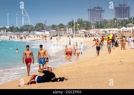 22. Februar 2021, Dubai, VAE: Menschenmassen spazieren am Sandstrand von JBR oder Jumeirah Beach Residence entlang. Urlauber schwimmen und sonnen sich Stockfoto