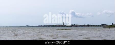 Panoramablick vom Uferbereich nahe West-Terschelling in Richtung Stadt mit deutlich sichtbarem Leuchtturm Brandaris auf einer klaren da Stockfoto