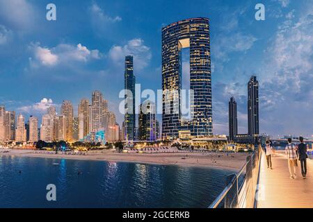 22. Februar 2021, Dubai, VAE: Panoramablick auf die Fußgängerbrücke mit Touristen, die zu zahlreichen Wolkenkratzern mit Hotels und Wohngebäuden auf der Stockfoto