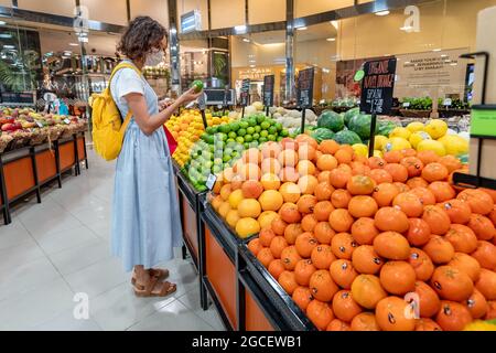 23. Februar 2021, Dubai, VAE: Kundin mit Gesichtsmaske, Einkaufen und Pflücken von Limetten- und Zitronenfrüchten im Supermarkt Stockfoto