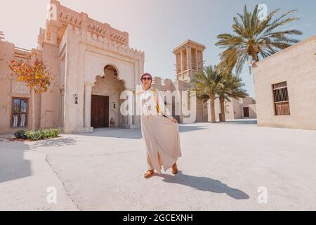 Eine Frau mit rotem Turban und langen Kleidern geht durch die alten engen Straßen von Bur Dubai und Creek. Reise- und Sightseeing-Konzept Stockfoto