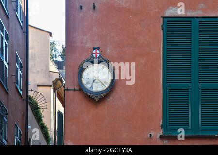 Eine alte Wanduhr mit dem Stadtwappen an der Außenwand eines alten Hauses im historischen Zentrum von Genua, Ligurien, Italien Stockfoto