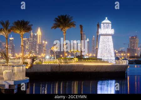 Beleuchteter dekorativer Leuchtturm in der Nähe des Parkplatzes von Yachten und Schiffen im Hafen von Dubai Creek Marina. Reise- und Touristendestinationen Stockfoto