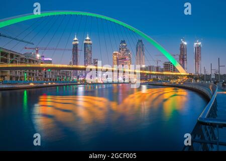 In grüner Farbe beleuchtete Tolerance Bridge in Dubai mit einem ungewöhnlichen architektonischen Design vor der Kulisse von Wolkenkratzern. Urbanismus und Sehenswürdigkeiten Stockfoto