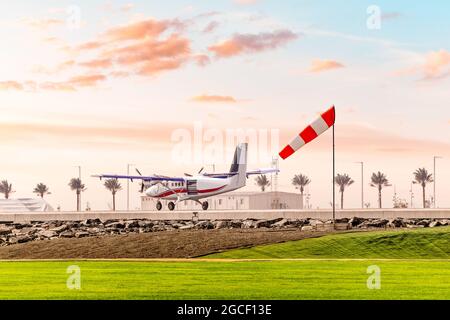Die Windsocke zeigt die Geschwindigkeit und Scherung auf dem Flugplatz beim Start eines leichten zweimotorigen Flugzeugs Stockfoto