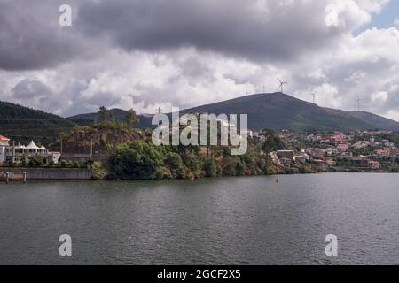 Kleines Dorf im Douro-Flusstal mit einem Moutain mit Windturbinen im Hintergrund, Portugal Stockfoto