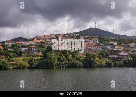 Kleines Dorf im Douro-Flusstal mit einem Moutain mit Windturbinen im Hintergrund, Portugal Stockfoto