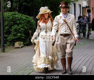 Henrichenburg, Waltrop, Deutschland. August 2021. Volle Kraft voraus! Zwei kostümierte Enthusiasten auf dem Weg zum Festival. Steampunk-Fans und Besucher, viele davon in voller retro-futuristischer Optik, treffen sich zum sencond day des´Steampunk Jubilee Market´ Festivals am historischen Wahrzeichen Henrichenburg-Bootsklift auf dem Dortmund-Ems-Kanal, heute ein Industriedenkmal. Die alten Strukturen und Boote bilden eine stimmungsvolle Kulisse für das Outdoor-Festival. Kredit: Imageplotter/Alamy Live Nachrichten Stockfoto