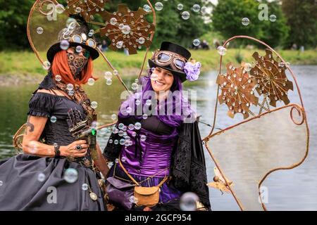 Henrichenburg, Waltrop, Deutschland. August 2021. Volle Kraft voraus! Zwei Steampunk-Performer aus 'Cherrystone' in Pose am Kanal. Steampunk-Fans und Besucher, viele davon in voller retro-futuristischer Optik, treffen sich zum sencond day des´Steampunk Jubilee Market´ Festivals am historischen Wahrzeichen Henrichenburg-Bootsklift auf dem Dortmund-Ems-Kanal, heute ein Industriedenkmal. Die alten Strukturen und Boote bilden eine stimmungsvolle Kulisse für das Outdoor-Festival. Kredit: Imageplotter/Alamy Live Nachrichten Stockfoto