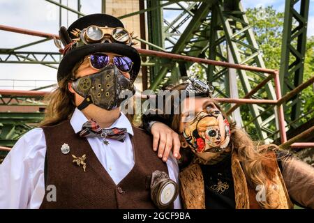 Henrichenburg, Waltrop, Deutschland. August 2021. Volle Kraft voraus! Zwei Steampunk-Enthusiasten in kreativen Outfits posieren in der Eisernen Boot Lift-Struktur. Steampunk-Fans und Besucher, viele davon in voller retro-futuristischer Optik, treffen sich zum sencond day des´Steampunk Jubilee Market´ Festivals am historischen Wahrzeichen Henrichenburg-Bootsklift auf dem Dortmund-Ems-Kanal, heute ein Industriedenkmal. Die alten Strukturen und Boote bilden eine stimmungsvolle Kulisse für das Outdoor-Festival. Kredit: Imageplotter/Alamy Live Nachrichten Stockfoto