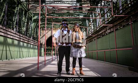 Henrichenburg, Waltrop, Deutschland. August 2021. Volle Kraft voraus! Zwei Steampunk-Enthusiasten in kreativen Outfits posieren in der Eisernen Boot Lift-Struktur. Steampunk-Fans und Besucher, viele davon in voller retro-futuristischer Optik, treffen sich zum sencond day des´Steampunk Jubilee Market´ Festivals am historischen Wahrzeichen Henrichenburg-Bootsklift auf dem Dortmund-Ems-Kanal, heute ein Industriedenkmal. Die alten Strukturen und Boote bilden eine stimmungsvolle Kulisse für das Outdoor-Festival. Kredit: Imageplotter/Alamy Live Nachrichten Stockfoto