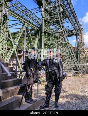 Henrichenburg, Waltrop, Deutschland. August 2021. Volle Kraft voraus! Zwei Steampunk-Enthusiasten in kreativen Outfits posieren in der Eisernen Boot Lift-Struktur. Steampunk-Fans und Besucher, viele davon in voller retro-futuristischer Optik, treffen sich zum sencond day des´Steampunk Jubilee Market´ Festivals am historischen Wahrzeichen Henrichenburg-Bootsklift auf dem Dortmund-Ems-Kanal, heute ein Industriedenkmal. Die alten Strukturen und Boote bilden eine stimmungsvolle Kulisse für das Outdoor-Festival. Kredit: Imageplotter/Alamy Live Nachrichten Stockfoto