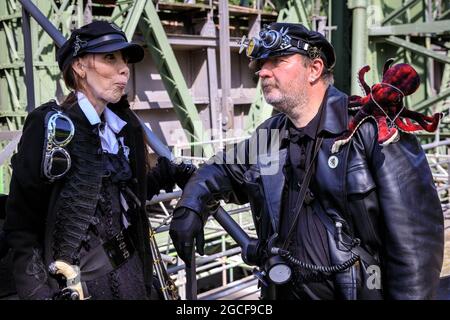 Henrichenburg, Waltrop, Deutschland. August 2021. Volle Kraft voraus! Zwei Steampunk-Enthusiasten in kreativen Outfits posieren in der Eisernen Boot Lift-Struktur. Steampunk-Fans und Besucher, viele davon in voller retro-futuristischer Optik, treffen sich zum sencond day des´Steampunk Jubilee Market´ Festivals am historischen Wahrzeichen Henrichenburg-Bootsklift auf dem Dortmund-Ems-Kanal, heute ein Industriedenkmal. Die alten Strukturen und Boote bilden eine stimmungsvolle Kulisse für das Outdoor-Festival. Kredit: Imageplotter/Alamy Live Nachrichten Stockfoto