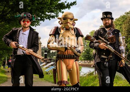 Henrichenburg, Waltrop, Deutschland. August 2021. Steam Wars – ein Retro-Stormtrooper und seine Steampunk-Freunde nähern sich. Steampunk-Fans und Besucher, viele davon in voller retro-futuristischer Optik, treffen sich zum sencond day des´Steampunk Jubilee Market´ Festivals am historischen Wahrzeichen Henrichenburg-Bootsklift auf dem Dortmund-Ems-Kanal, heute ein Industriedenkmal. Die alten Strukturen und Boote bilden eine stimmungsvolle Kulisse für das Outdoor-Festival. Kredit: Imageplotter/Alamy Live Nachrichten Stockfoto