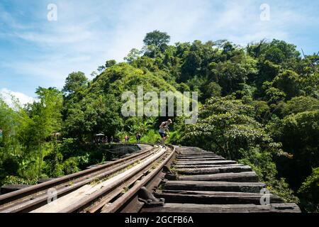 Amada, Antioquia, Kolumbien - Juli 18 2021: Ein junger Kaukasusmensch geht über die Brücke der alten Rustikalen Eisenbahn mitten in einem Wald voller Wälder Stockfoto