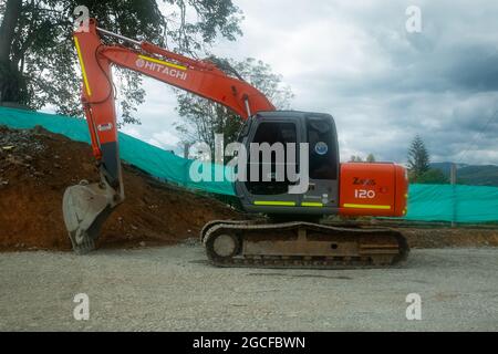 Amada, Antioquia, Kolumbien - Juli 18 2021: Orange Crane entfernt einen Erdhaufen für den Bau einer neuen Fahrbahn Stockfoto