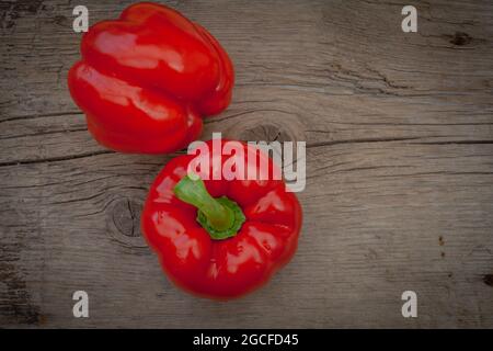 Rote Paprika mit glänzenden Wassertropfen auf rustikalem Holzhintergrund Stockfoto
