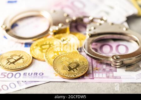 Euro-Banknoten, Bitcoins und Handschellen. Münzen einer Kryptowährung. Stockfoto