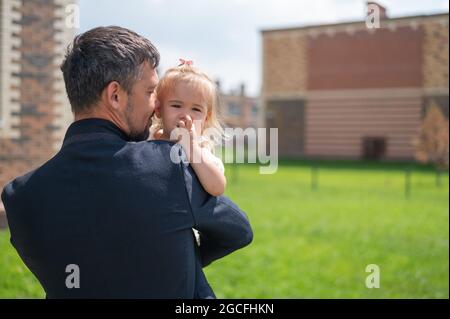 Der liebevolle Vater hält sich draußen an die Hände seiner kleinen Tochter. Stockfoto