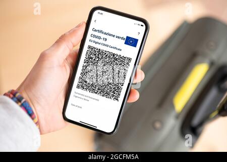 (Selektiver Fokus) Überkopfansicht einer menschlichen Hand, die ein Smartphone mit dem Green Pass hält. Stockfoto