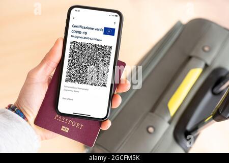 (Selektiver Fokus) Ansicht von einer menschlichen Hand, die einen Pass und ein Smartphone mit dem Green Pass hält. Stockfoto