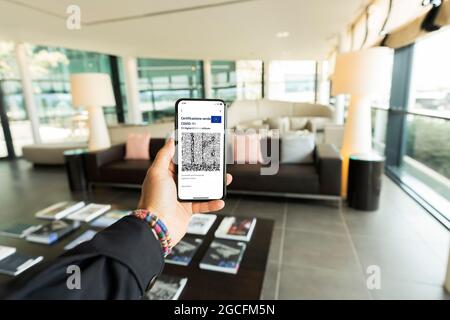 (Selektiver Fokus) Überkopfansicht einer menschlichen Hand, die ein Smartphone mit dem Green Pass hält. Stockfoto