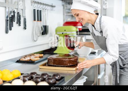 Patissier gießt flüssige Schokolade auf einem Kuchen Stockfoto