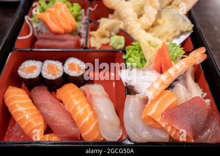 Selektiver Fokus und Draufsicht im Sushi Bento Box Set enthalten Lachs und Thunfisch Nigiri, Brötchen, Tempura und Sashimi. Stockfoto