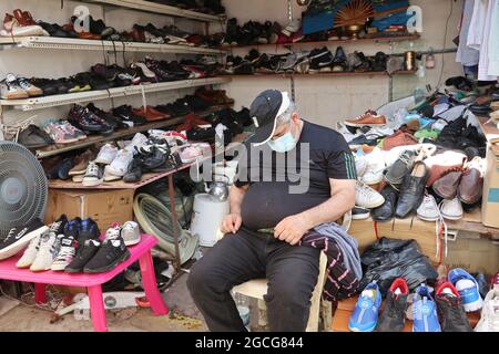 Beirut, Libanon. August 2021. Ein alter Schuhhändler rast am 8. August 2021 auf dem Souq el Ahad (Sonntagsmarkt) in Beirut, Libanon. Die Preiserhöhung ist für den Libanon zu einem harten Problem geworden, da mehr als die Hälfte der Bevölkerung seit Beginn der Wirtschafts- und Finanzkrise im Jahr 2019 unter die Armutsgrenze gefallen ist. Die Mittelschicht ist weggewischt worden und immer weniger Menschen können es sich leisten, in den Geschäften Schuhe und Kleidungsstücke zu kaufen.(Foto: Elisa Gestri/Sipa USA) Quelle: SIPA USA/Alamy Live News Stockfoto
