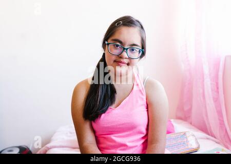 Porträt eines lateinischen Teenagers mit Down-Syndrom in ihrem Zimmer, im Behindertenkonzept in Lateinamerika Stockfoto