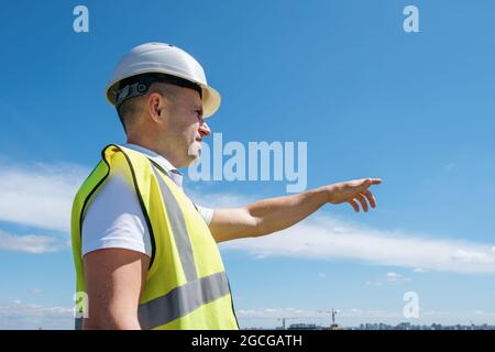 Baumeister im weißen Helm zeigt mit seiner Hand auf der Baustelle Stockfoto