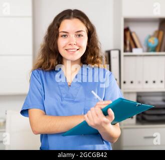 Positive Ärztin in blauem Hemd im medizinischen Zentrum stehend Stockfoto