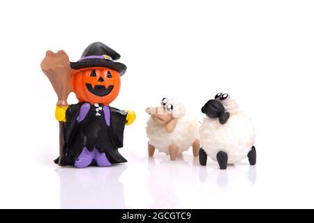 Kleine Keramik Kürbis Hexenpuppe mit zwei Schafen auf weißem Hintergrund für halloween Feier. Stockfoto