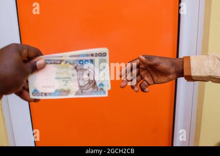 Zwei afrikanische Hände, die nigrische Naira-Scheine, Bargeld oder Währung erhalten oder tauschen Stockfoto