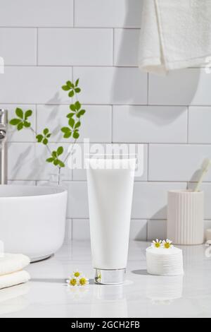 Kosmetikprodukt und Baumwollhandtücher, Baumwollkissen mit grüner Pflanze auf weißem Tisch in einem Badezimmer Hintergrund Keramik Stockfoto