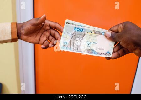 Zwei afrikanische Hände, die nigrische Naira-Scheine, Bargeld oder Währung erhalten oder tauschen Stockfoto