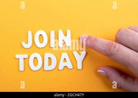 Machen Sie Noch Heute Mit. Geschäftskonzept. Weiße Buchstaben und die Hand einer Frau auf einem gelben Papierhintergrund. Stockfoto