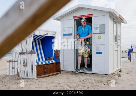 Westerland, Deutschland. Juli 2021. Der Strandstuhlwärter Mathias Tognino tritt zu Beginn seiner Schicht aus seiner Mietstation am Strand von Westerland auf der Insel Sylt hervor. (To dpa - Sommerserie 'hinter den Kulissen des Tourismus im Norden' - 'Sylt Strandsessel-Anwärter hält die Ruhe am Strand vor Westerland') Quelle: Frank Molter/dpa/Alamy Live News Stockfoto