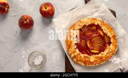 Pfirsich-Gallete auf Backpapier auf Holzhintergrund. Frisch zubereiteter hausgemachter Kuchen. Draufsicht, flach liegend Stockfoto